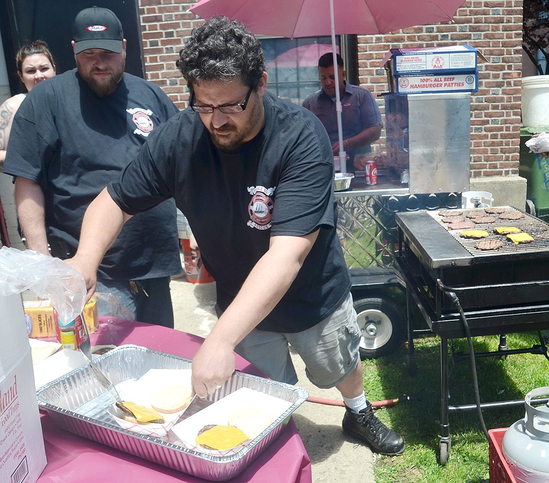 As a recent recruit on the Rescue 40 team, firefighter John Santarsiero grills up burgers and places them into trays for community members enjoying the afternoon at the fire station.