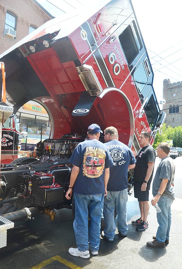 After lifting the head of the new Reliance Engine & Hose Company water pumper, firefighters gather around to check out the enormous engine.