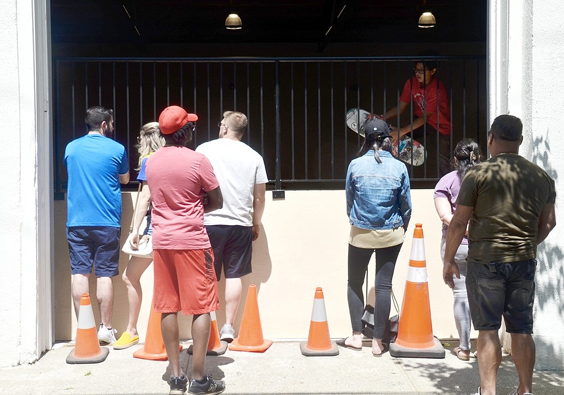 Spectators gather outside the Wilkins Avenue indoor private park to watch local skateboarders glide back and forth and competitively support each other while they try to master different tricks.