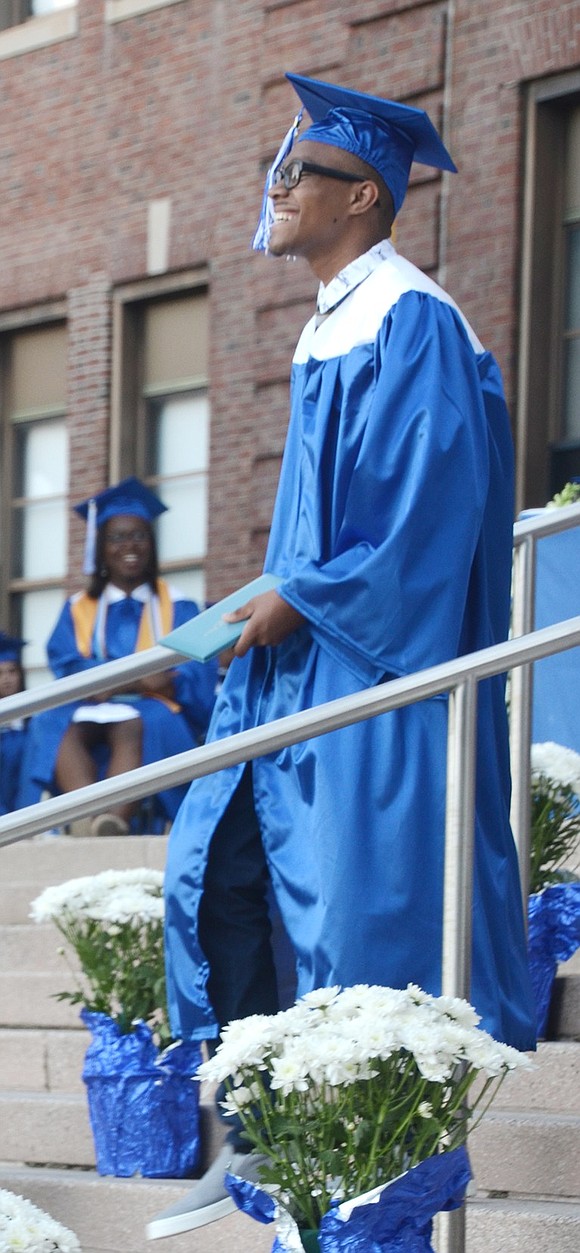 A grin of pure joy stretches across J’Amor Clark’s face as he walks down the stairs with his diploma.