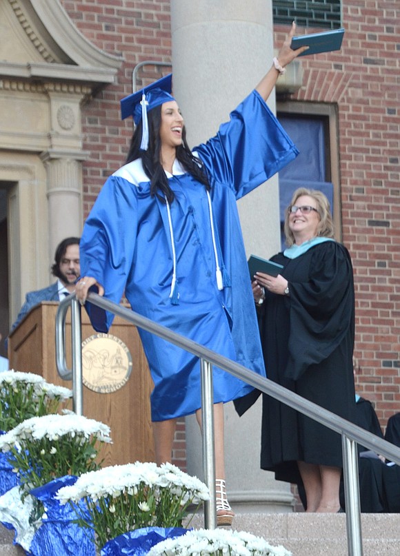 After Marcella Zanetti receives her diploma from Business Administrator Sandra Clohessy, she waves at her animated family as they roar from the bleachers.