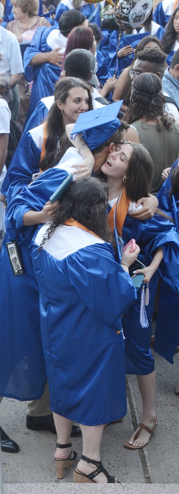 When the ceremony is over and friends, family and graduates merge to celebrate in the flag plaza, Zavier Garcia leans over to embrace Genevieve Pastena in a hug.