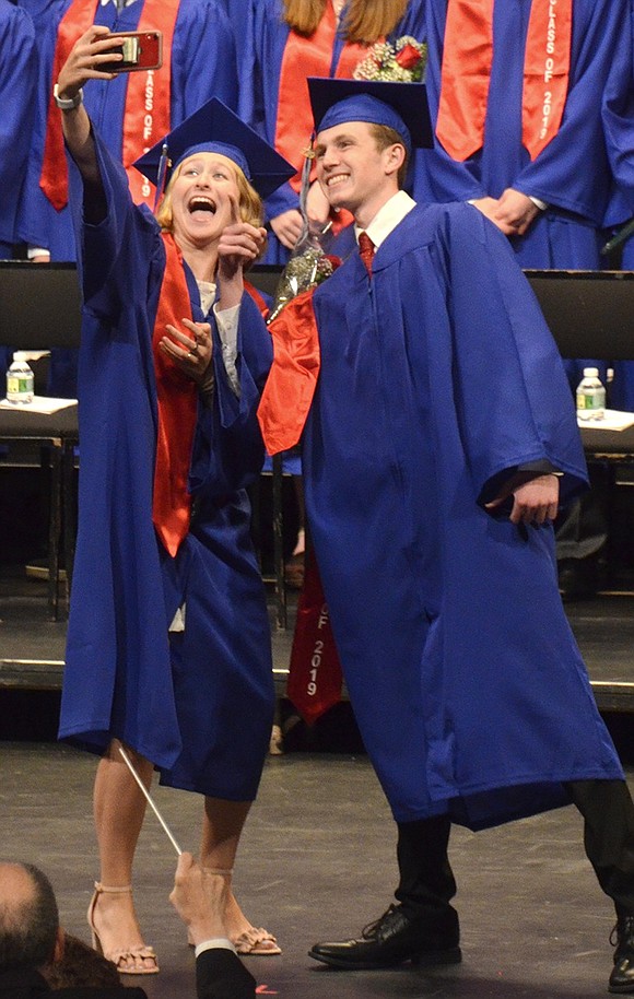 Before taking their seats on the stage, Abigail Strauzer and Ryan Wallace stop to take a selfie. As students filed onto the stage, many collaborated with their walking partner to do something cute.