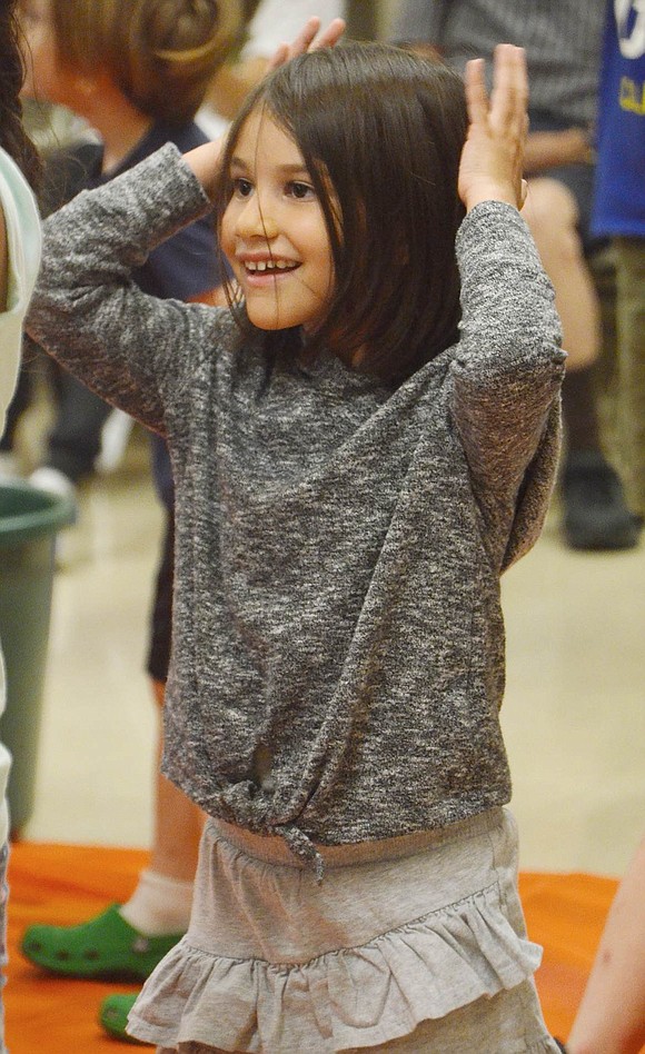 King Street Elementary School rising first-grader Emma Ramos smiles as she raises her hands in the air along with others while dancing to the “Chicken Dance.” 