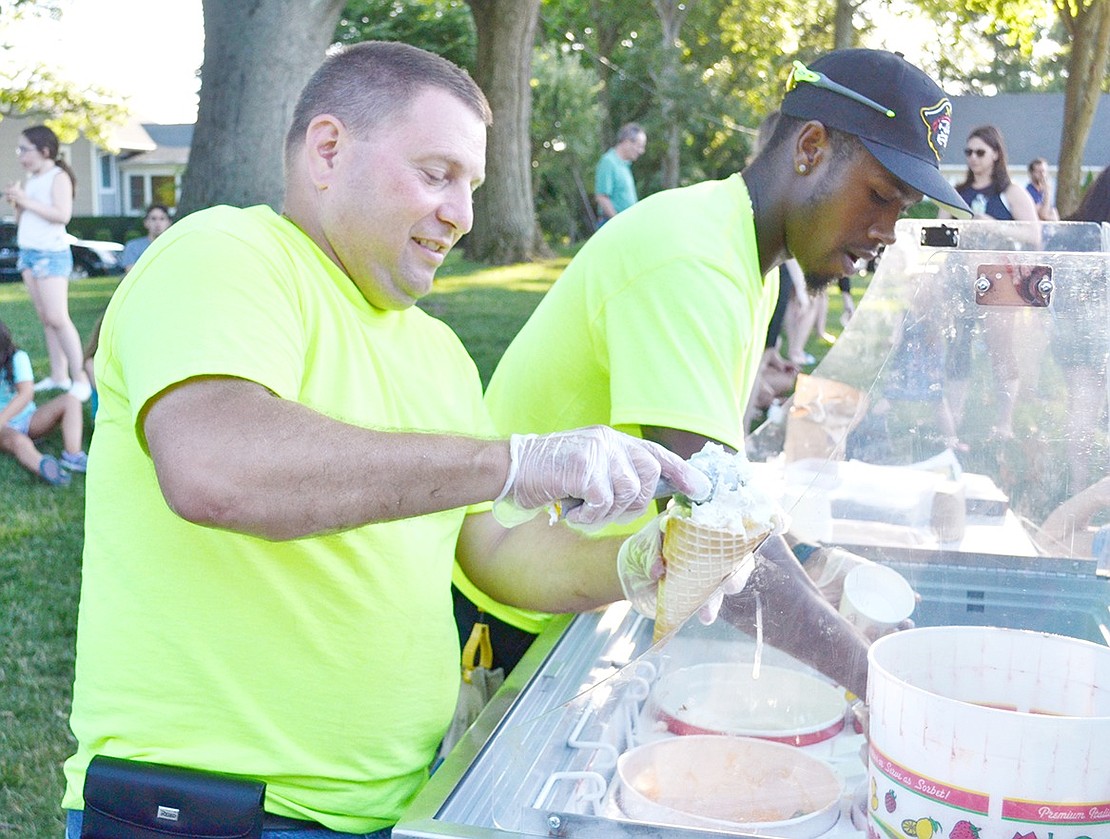 Rye Brook Highway Foreman Paul Vinci (left) piles heaping scoops of vanilla ice cream into a waffle cone for Ice Cream Friday visitors while new groundskeeper Zack Warren goes to serve some chocolate in a cup.