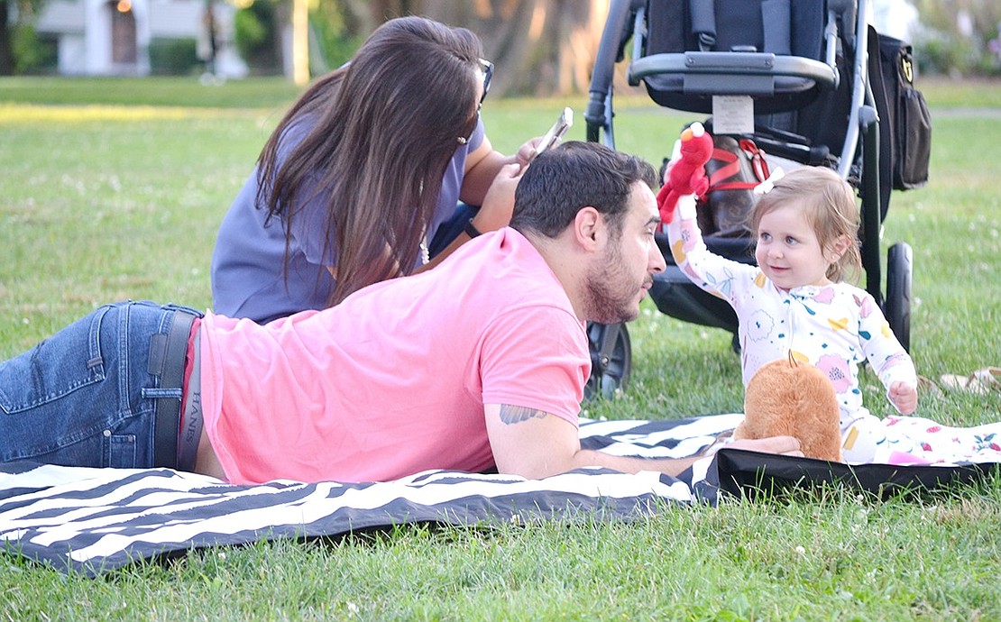 Locust Avenue resident Carly Miata bends down to take a video of her 1-year-old daughter Rosemary as she dances to the music on their blanket with Elmo and her father Vinny.