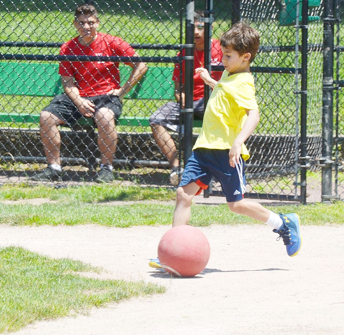 During the community kickball match, Ridge Street Elementary School rising third-grader Leon Samuels gets a running start to kick the ball before sprinting around the baseball diamond.