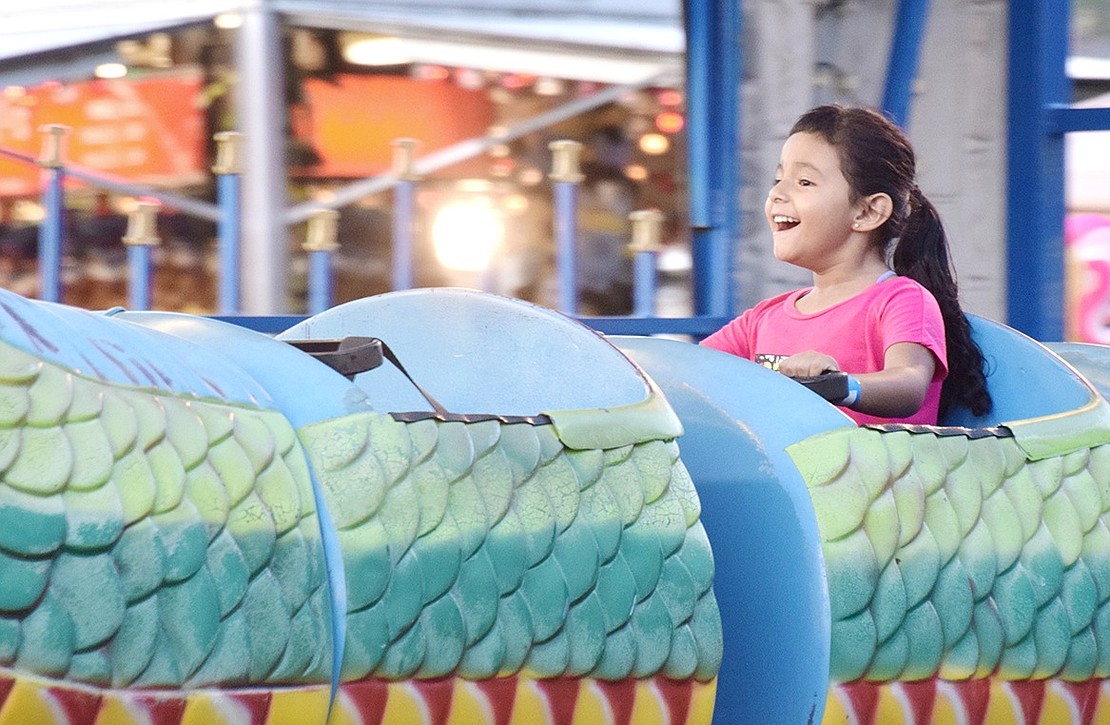 Oak Street resident Sofia Roque, 4, clutches the handle bars in front on her and shrieks with joy over the thrill of the dragon coaster .