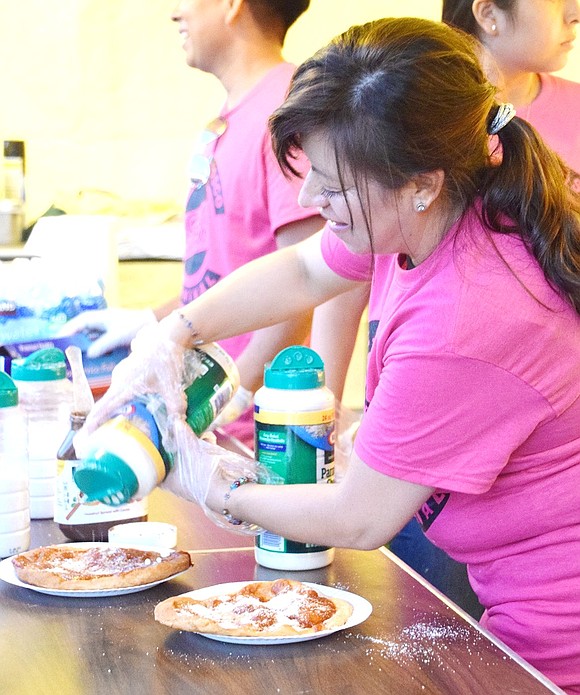 Elsy Maldonado delicately sprinkles parmesan cheese over pizza fritta before serving the classic carnival treat to hungry patrons. The Harrison resident is volunteering as a longtime member of the St. John Bosco Parish.