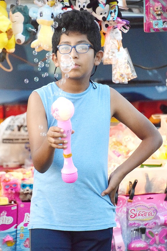 White Plains resident Diego Bejarttupa, 11, looks off in thought in the mist of bubbles surrounding his face that are blasting out of his new toy.