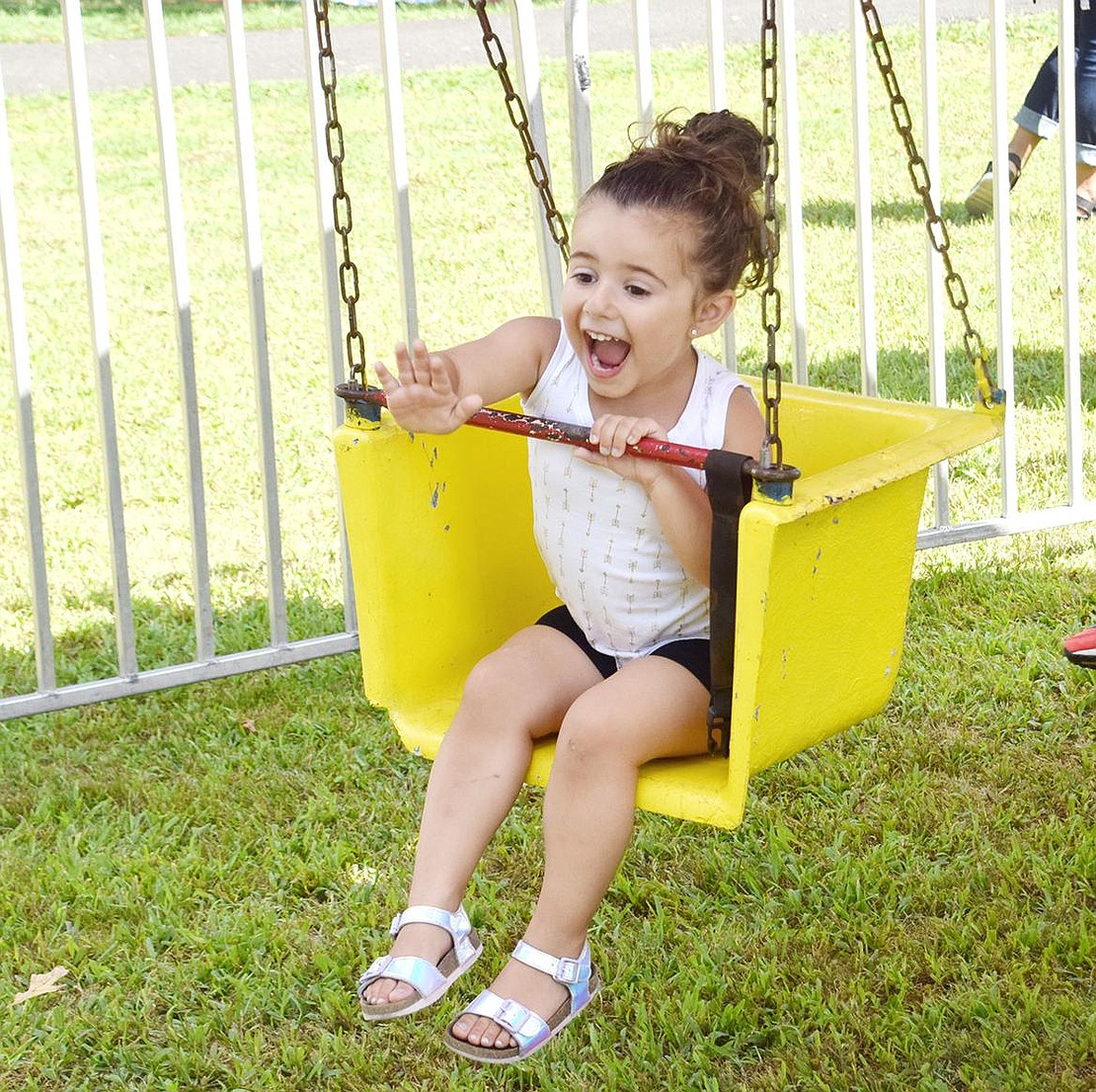 With a massive smile, Alessia Facciola waves at her family on the other side of the gate as she comes around on the swing ride. The Bedford 3-year-old is visiting her King Street-residing grandparents to enjoy Port Chester Day at Lyon Park on Saturday, Aug. 24.