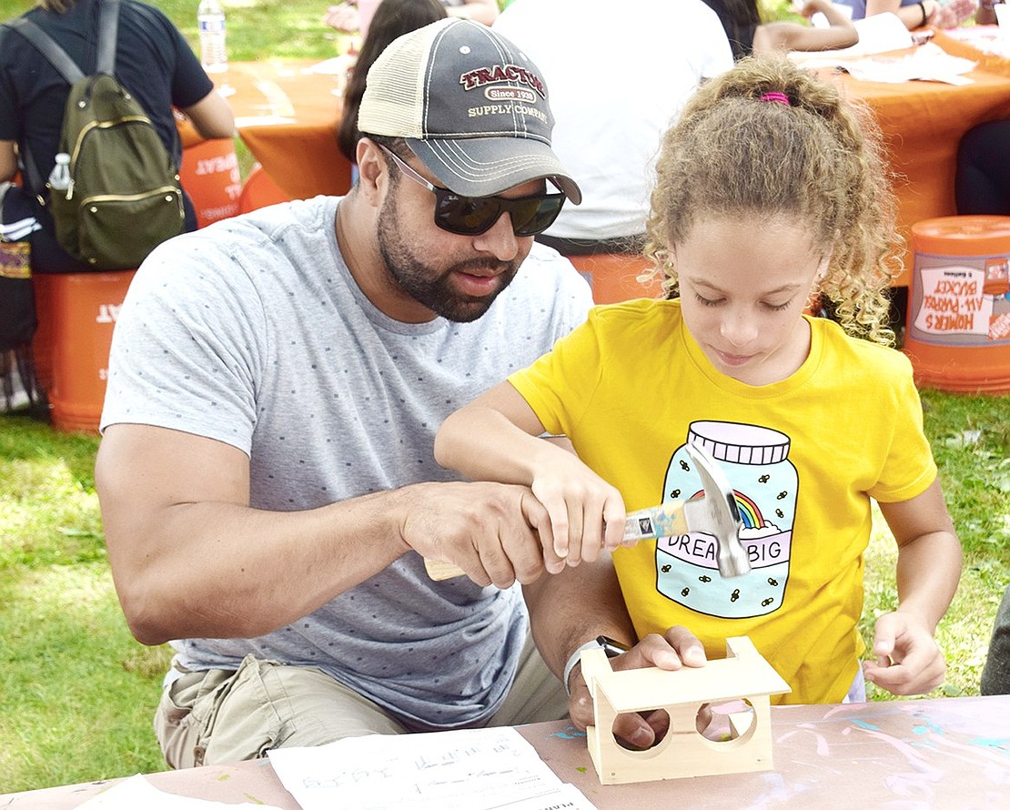 Dreaming big, 9-year-old Angelina Romano hammers together a plant starter set holder at the Home Depot craft table with the help of her father Bryant, the John F. Kennedy School assistant principal and Port Chester resident.