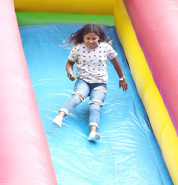 Port Chester Middle School rising sixth-grader Angie Garcia gets air as she bounces down the giant inflatable slide.