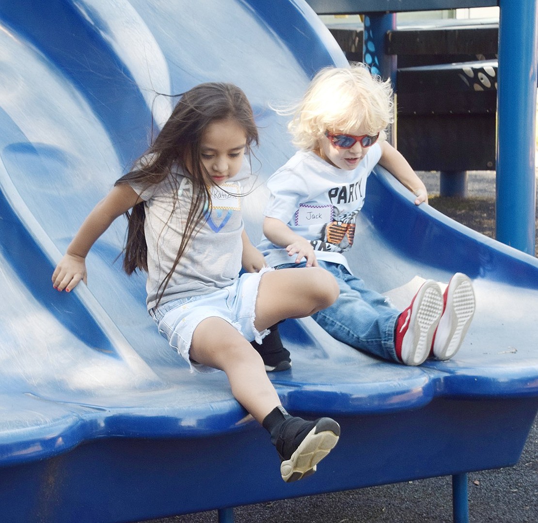 While goofing around on the John F. Kennedy upper building playground during the kindergarten Ice Cream Social on Tuesday, Sept. 3, William Street resident Katherine Duchimaza (left) races Summit Avenue resident Jack Zlabinger down the slide.