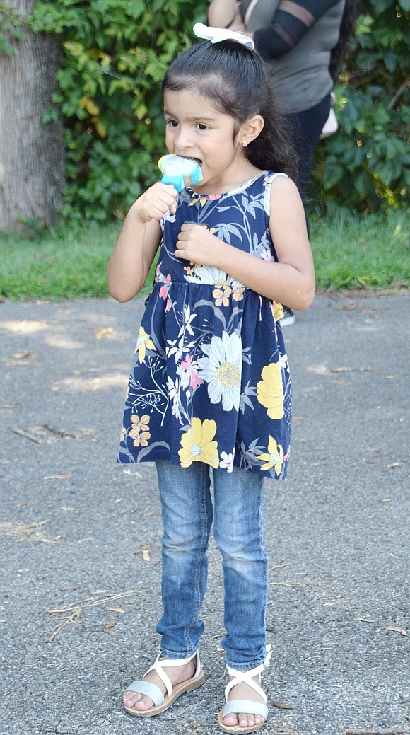 Fawcett Street resident Iliana Rodriguez, a John F. Kennedy School kindergartener, tries to avoid a brain freeze as she takes a big bite into her Jim’s Ice Cream Truck treat.