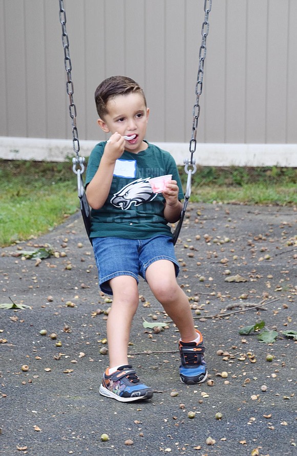 A true multi-tasker, Linden Street resident Luke Petriello gently rocks on a King Street playground swing while finishing off his strawberry ice cream cup.