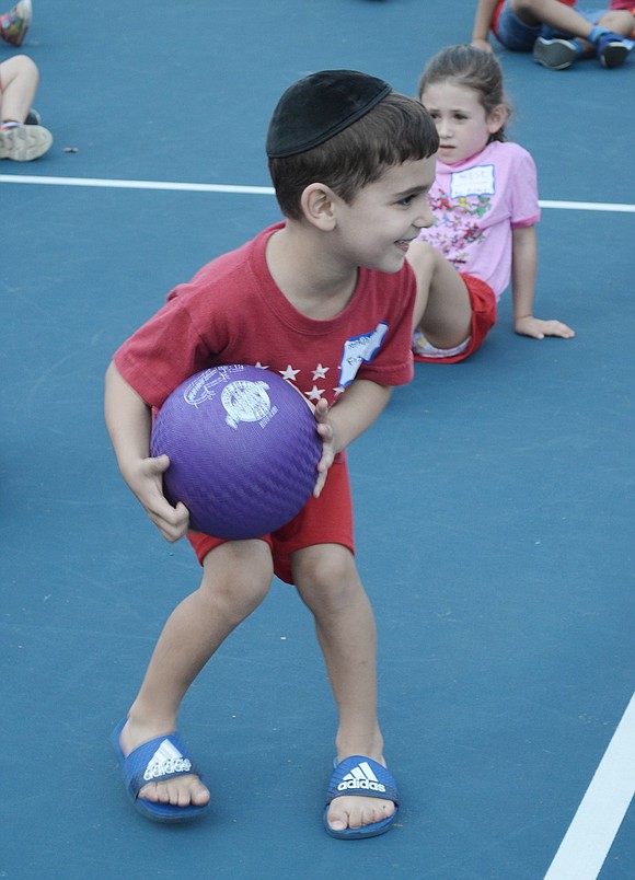 Rising kindergartner Yehuda Cywiak looks around the court to find the best passage to roll his ball and knock down his opponent’s pins during one of the games.