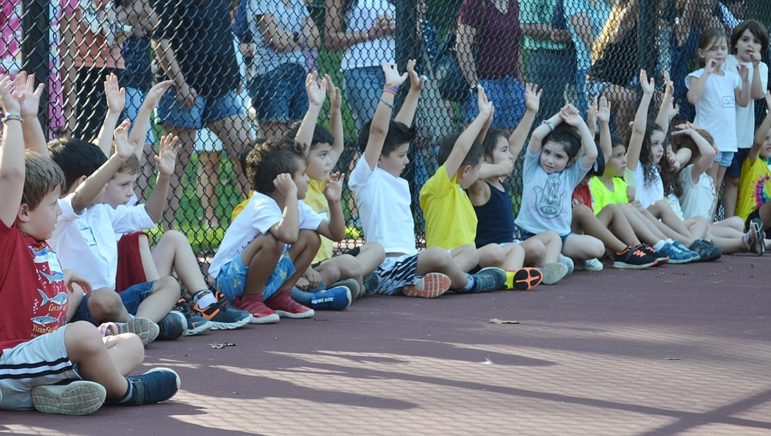 Students eagerly raise their hands to show who is ready to be a kindergartener at the Harkness Park tennis courts during the Kindergarten Social.