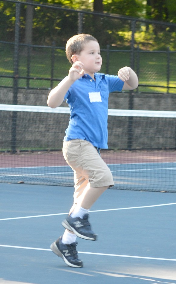 Rising kindergartner Justin Crasper jumps as he competes with his fellow classmates to see who can get across the tennis courts and back first.