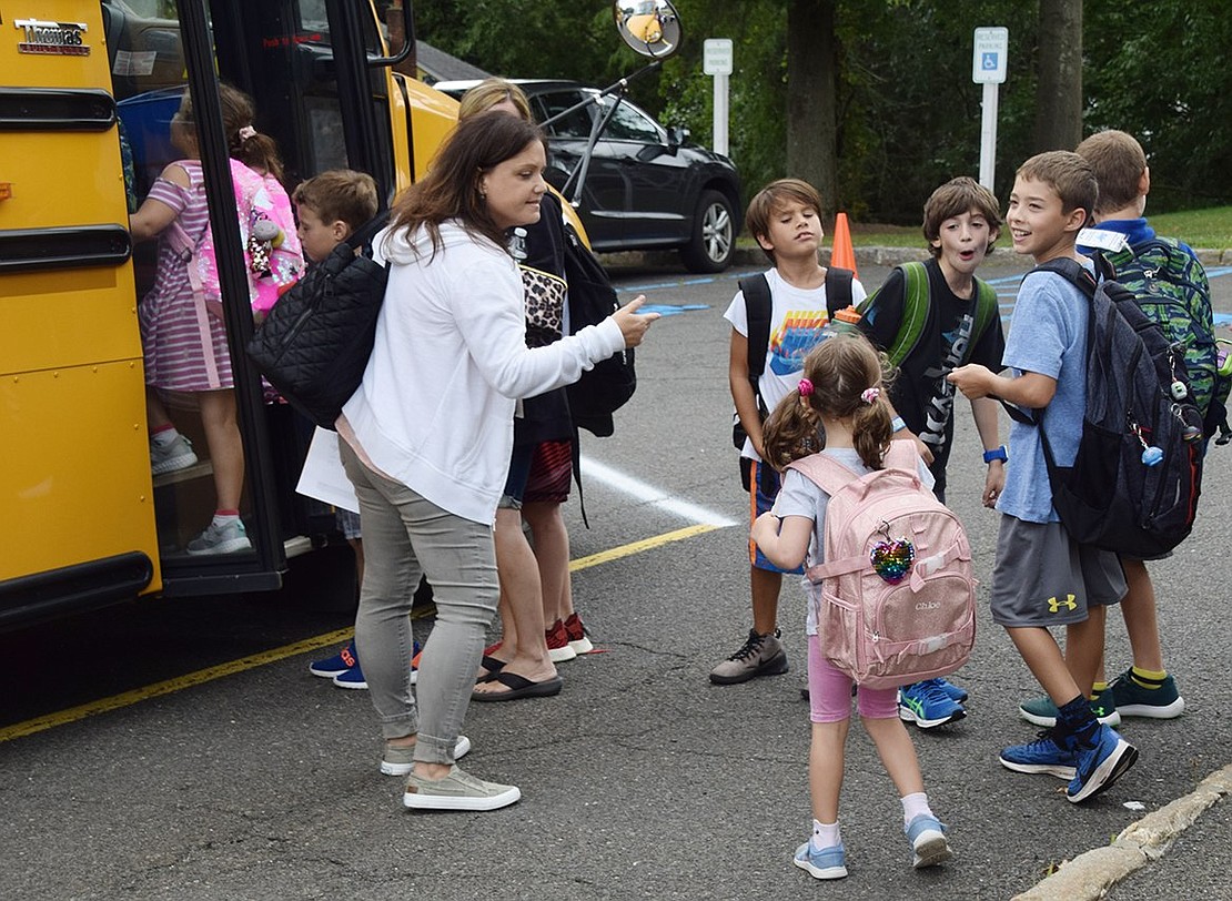 Students from various grades quickly begin piling into a school bus after their second day of class.