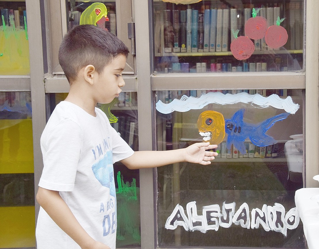 Park Avenue School third-grader Alejandro Yanez points to the spooky “pumpkin head shark” he painted.
