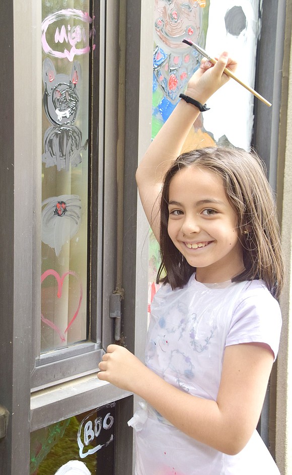 With true artist pizazz, Ridge Street School fourth-grader Ana Mattinson takes a moment away from painting her black cat on the library to smile for the camera.