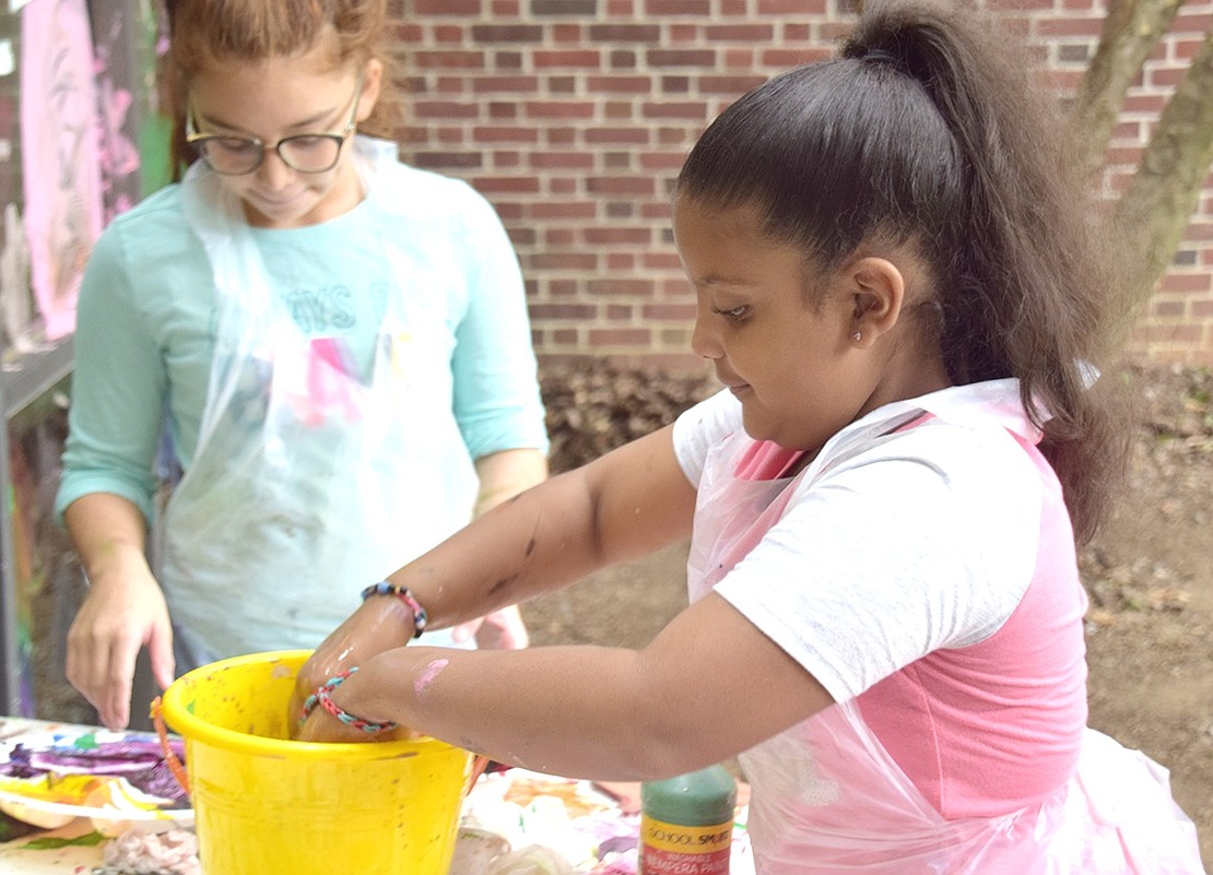 Bronx resident Madyson Marte, the 8-year-old daughter of a library staff member, washes off her paint brushes in a bucket of water.