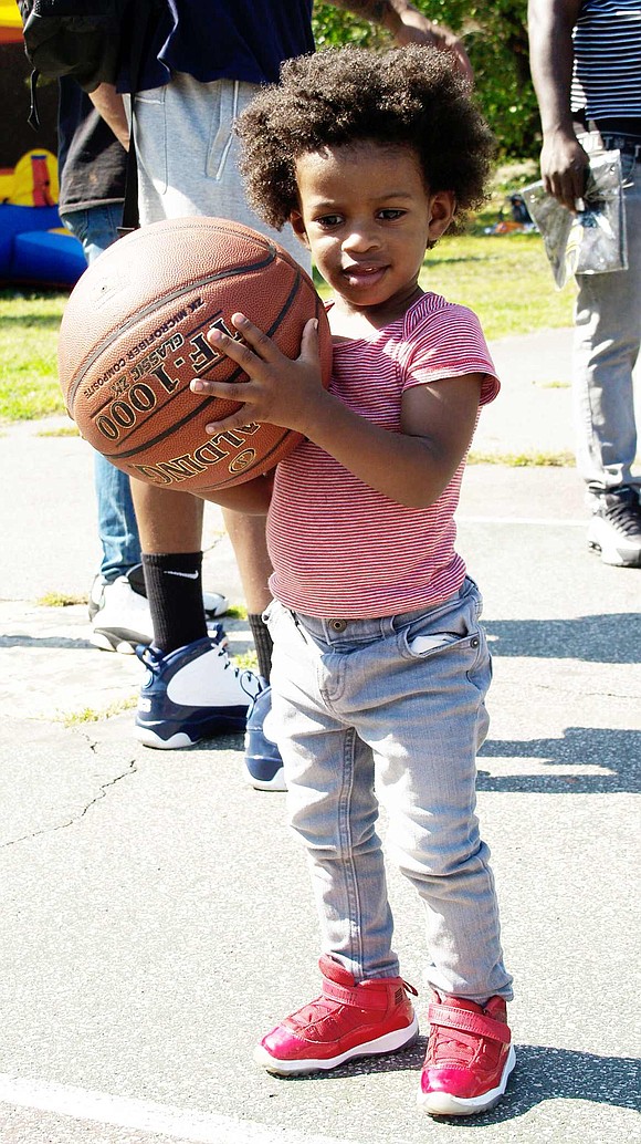 Holding a basketball almost half his size, one-year-old Westchester Avenue resident Mason Moody gets ready for his turn to shoot the ball. 