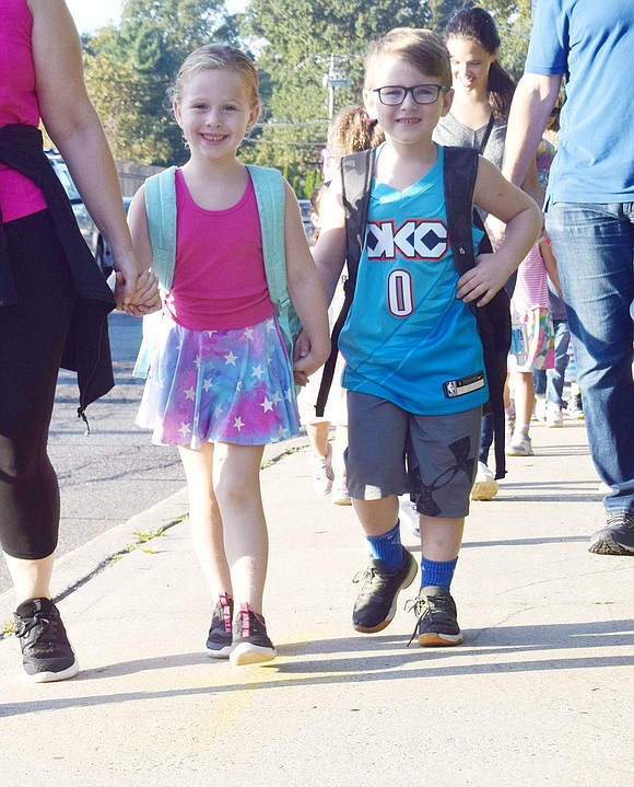 First-grader David Gitkind smiles as he holds the hand of his sister Abigail, a kindergartner, as they make their way to school.