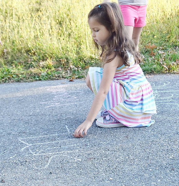 Kindergartner Skylar Koransky is one of the first to chalk in her name on a sidewalk outside of Ridge Street School to showcase that she walked all the way from home.