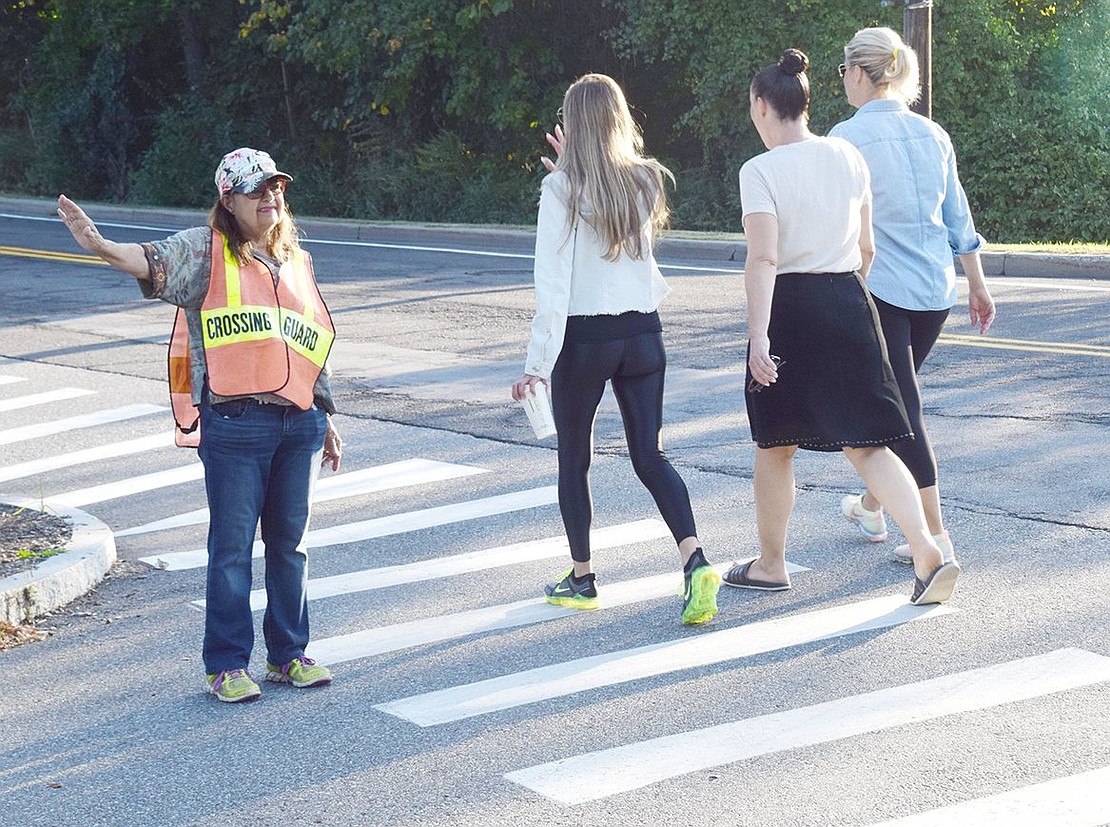 Crossing guard Linda Kochanowicz stops oncoming traffic on Rockinghorse Trail to allow walkers to cross the street.