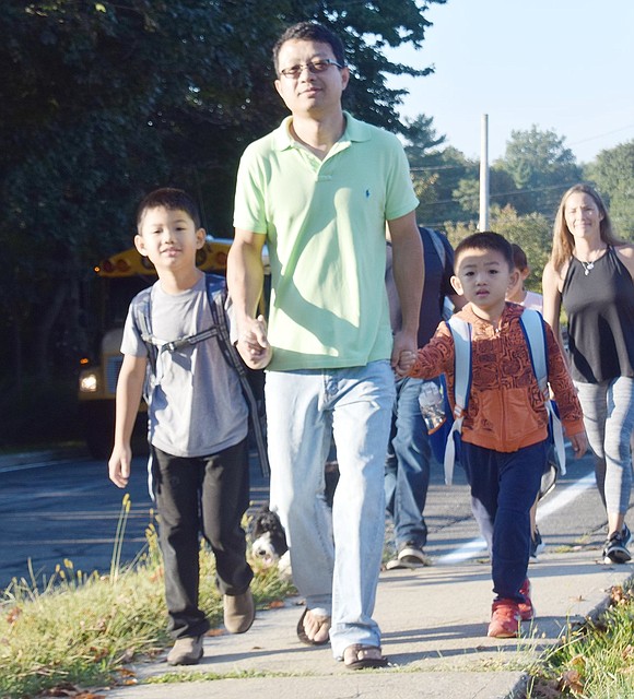 Kindergartner Jason Zhou (right) and his third-grade brother Ethan hold their father Sean’s hands as they walk up the hill to Ridge Street School.