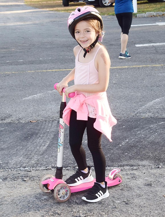 First-grader Shannon Murphy, 5, pauses from her scootering to smile during International Walk to School Day.