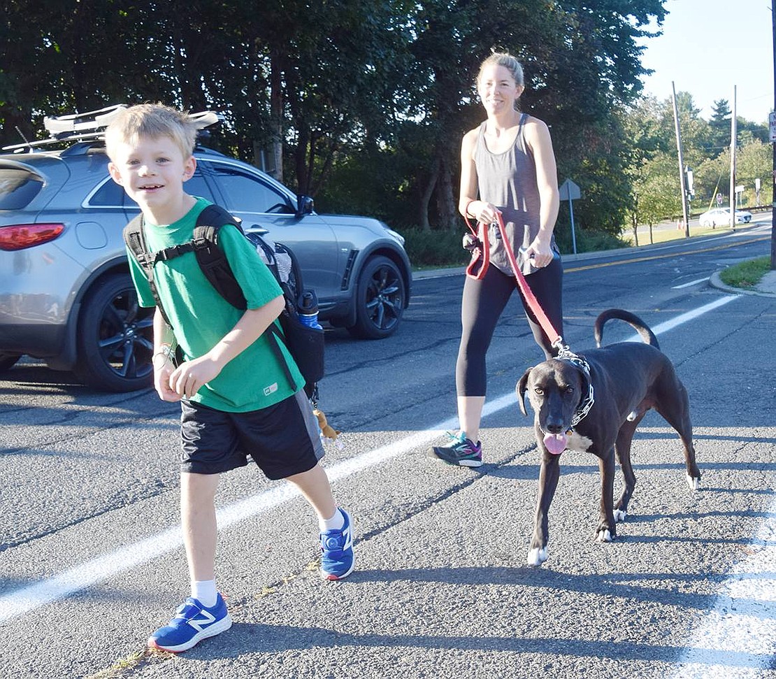 Accompanied by his dog Bruce, Knollwood Drive resident James Vnenchak, 8, walks up the hill toward Ridge Street School with his mom Catherine.