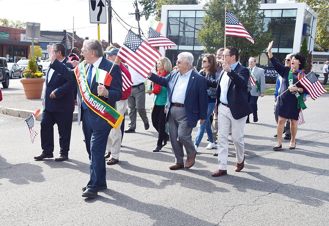 While waving American and Italian flags, Grand Marshal Tom Kissner leads local politicians down the road during the procession.