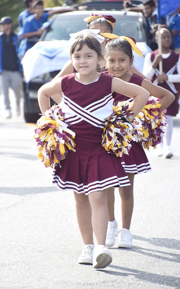 With proper form, King Street School third-grader Emma Santos heads the line of other cheerleaders marching in the Columbus Day Parade.