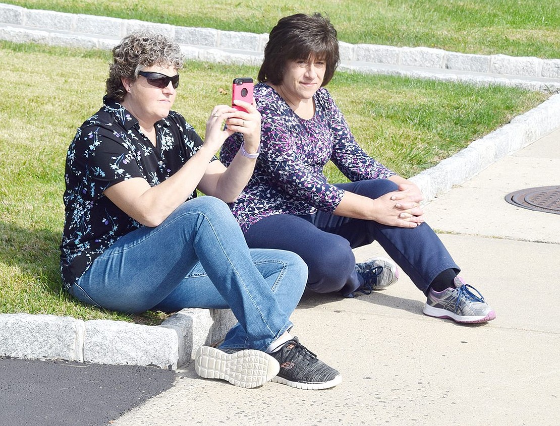 Christine Yozzo (left) takes her phone out to record the blaring fire trucks beginning the parade at the top of Westchester Avenue. The Utica resident was visiting her cousin Stephanie Gerardi (right), a Monroe Place resident.