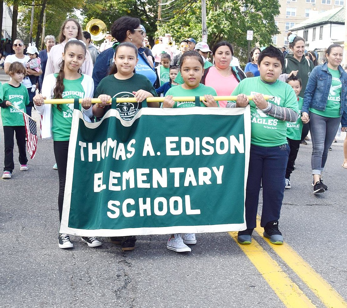 All proudly sporting their green school shirts, Edison Elementary School students walk in the procession together while holding up their school’s banner.