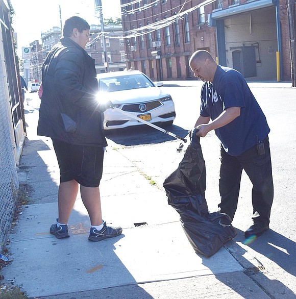 Port Chester Department of Public Works General Foreman Rocco Cambareri and his son John, a sophomore at Somers High School, pick up bits of trash off an Irving Avenue sidewalk.