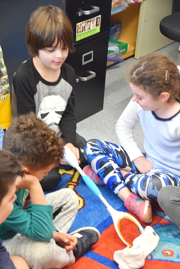 Kindergartener Emerson Andruk tries to pick up a sock during a demonstration showing how people with vision impairments may use this apparatus to become more independent.