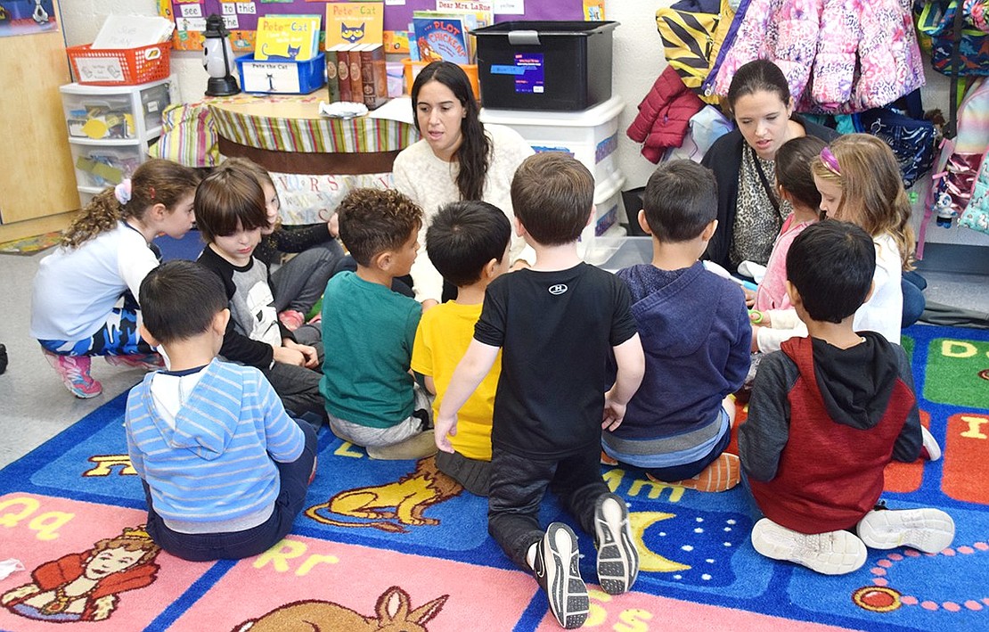 Parent volunteers Courtney Schlesinger (left) and Shana Koransky teach kindergartners how to use devices people with vision impairments may use.