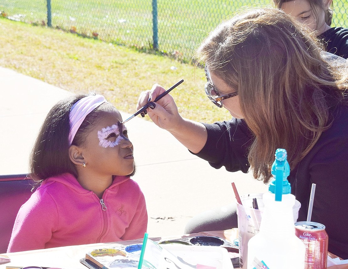 Westchester Avenue resident Cali Moody, 4, sits patiently as North Regent Street resident and volunteer Dena McConnell paints a bat on her face. Games, food trucks and other activities were enjoyed by many at the annual Harvest on Park fall carnival hosted by the Park Avenue School PTO on Saturday, Oct. 19.