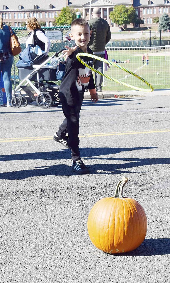 Olivia Street resident Louis Rytelewski, 7, throws a hula hoop onto a pumpkin to win a tossing game at the carnival.