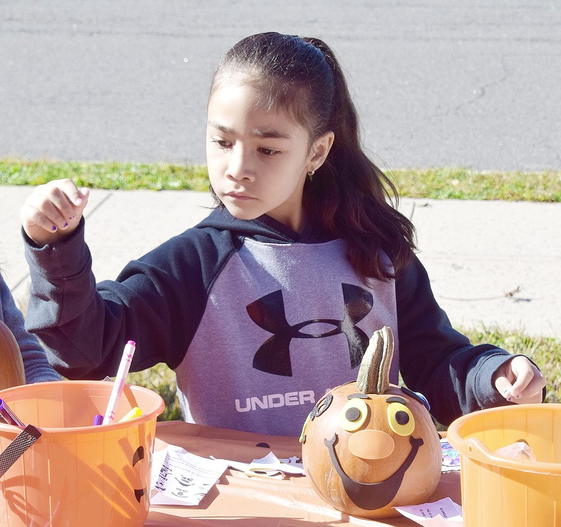 Park Avenue School student Kayla Castro, 7, analyzes all the colored markers available to her before returning to decorating her smiley faced pumpkin.