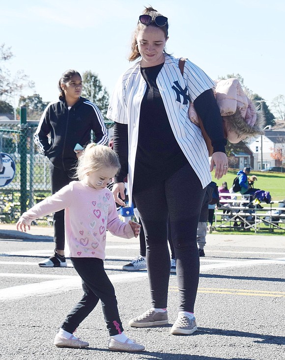 White Plains resident Maureen Bateman looks on as her daughter Abbey, 3, stomps her right foot to the “Cha-Cha Slide” in the middle of the closed off street in front of Park Avenue School.