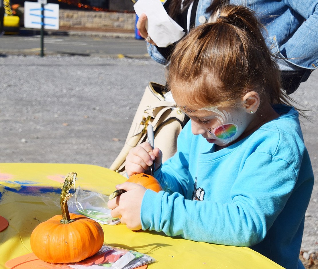 Ridge Street School first-grader Siena Escott focuses on designing a spooky face on her miniature pumpkin at Blind Brook PTA’s annual Fall Fest on Saturday, Oct. 26. The Ridge Street School front parking lots were closed off to house food trucks, makeup artists, pumpkin decorating stations and other activities for families.