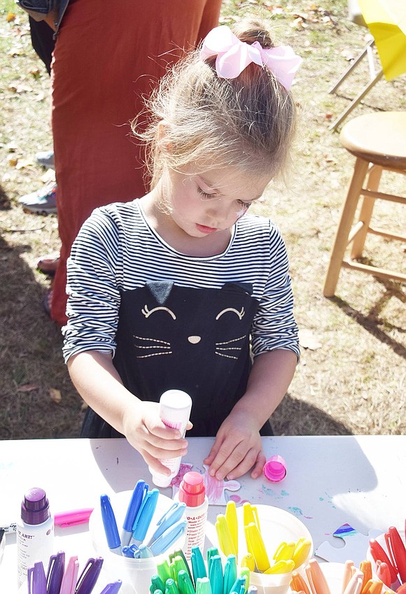 White Plains resident Clara Renz, 4, stamps a puzzle piece with pink paint. The piece was added to a large collaborative puzzle created by others. 