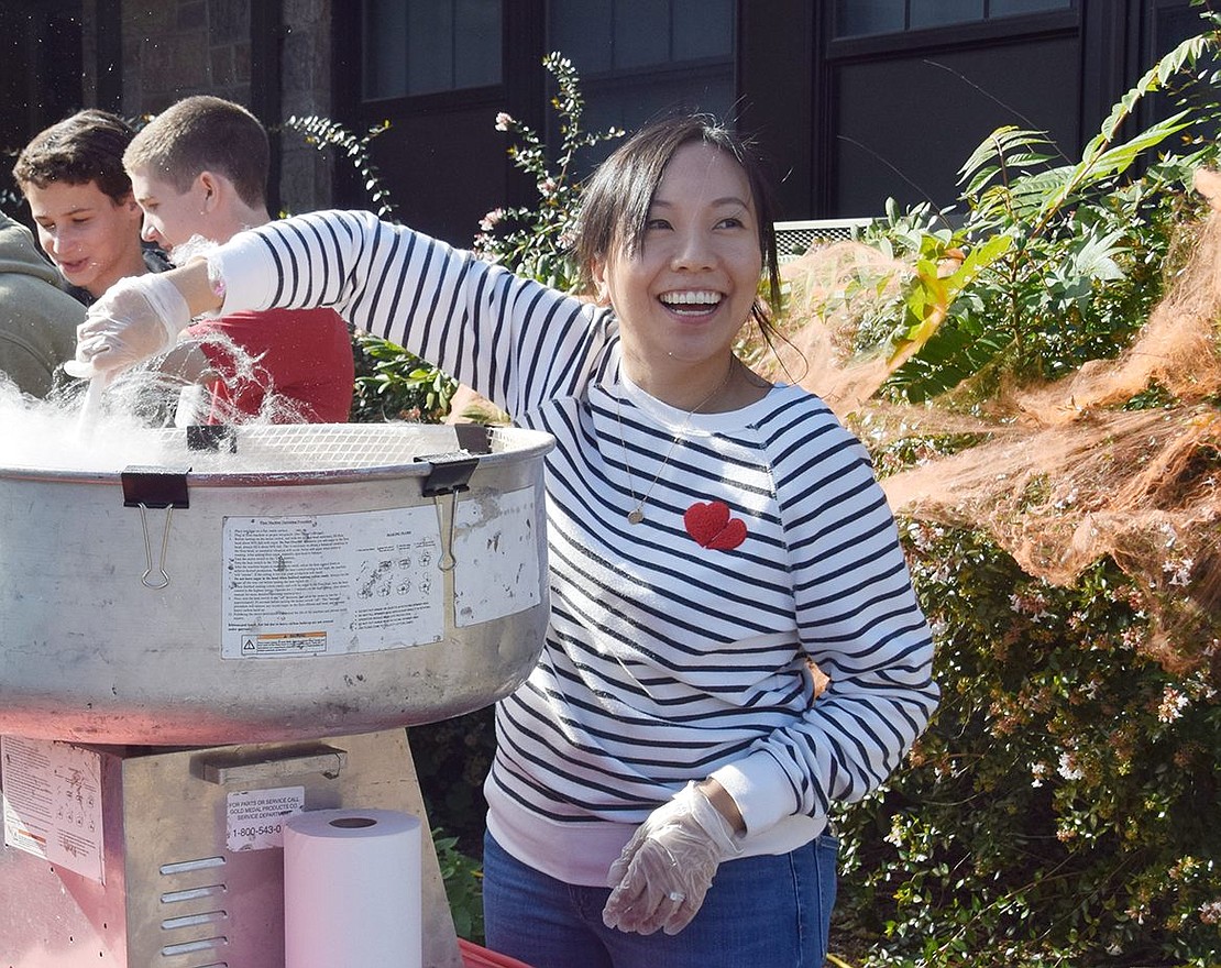 Fall Fest volunteer Edris Park, a Bonwit Road resident, rolls pink cotton candy onto a stick for a lucky child.