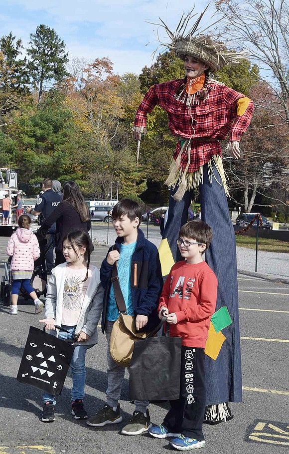 Cirque du Jour performer Tanya Turgeon stands on stilts as a giant scarecrow and poses with Ridge Street students Lizzie Odisharia (left), Sozari Odisharia and Nicholas Bouadze.