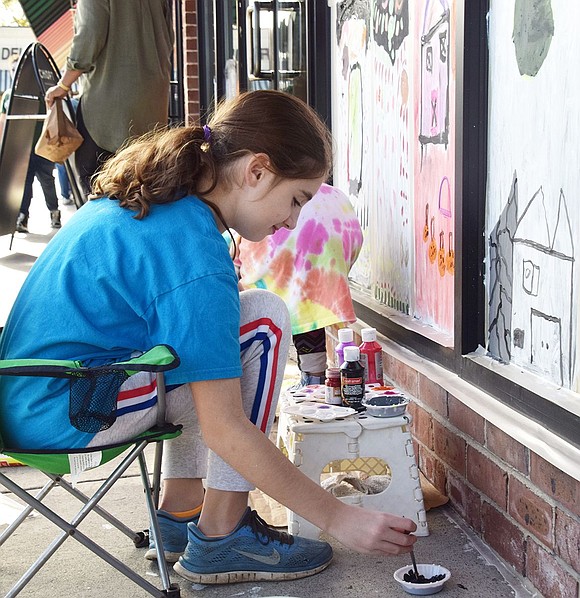 Ridge Street School fifth-grader Holly O’Neill, 9, dips her paintbrush in black paint to add more detail to her haunted house scene. O’Neill was one of about 60 children who painted windows in a Halloween theme around the Rye Ridge Shopping Center on Saturday, Oct. 26.